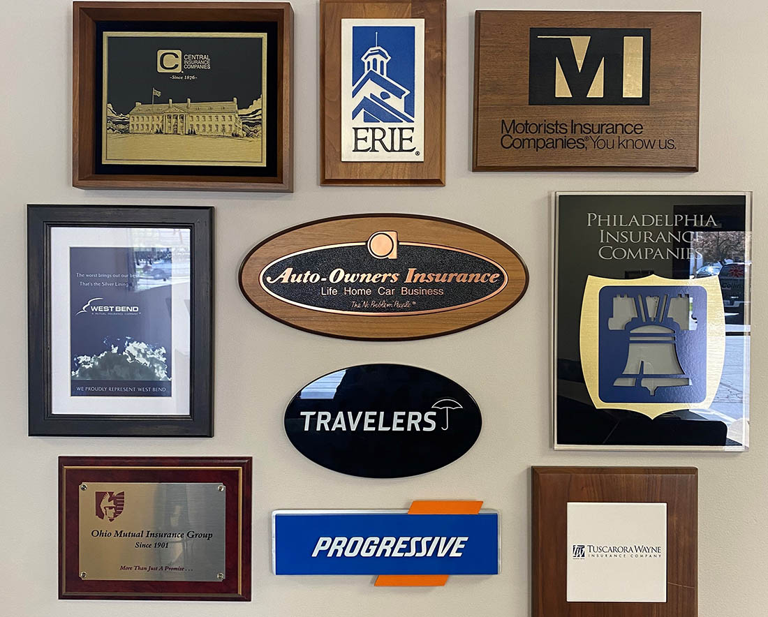 Homepage - Madison-Collins-Stephens Agency Office Wall with Awards, Carrier Logos, and Framed Items Hanging Up